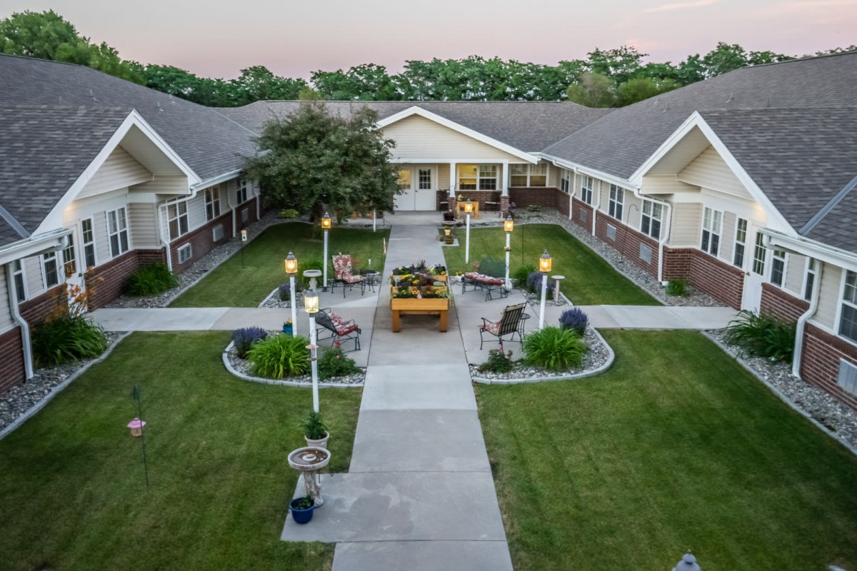 A pleasant courtyard with a pathway leading to a central seating area, flanked by well-maintained lawns and surrounding buildings.