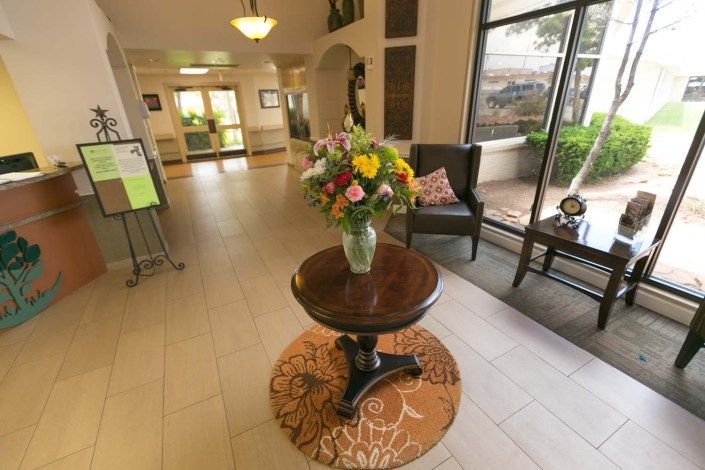 A hotel lobby with a central table displaying a vase of colorful flowers.