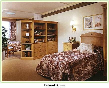 A cozy patient room with two beds, wooden furniture, and decorative elements.