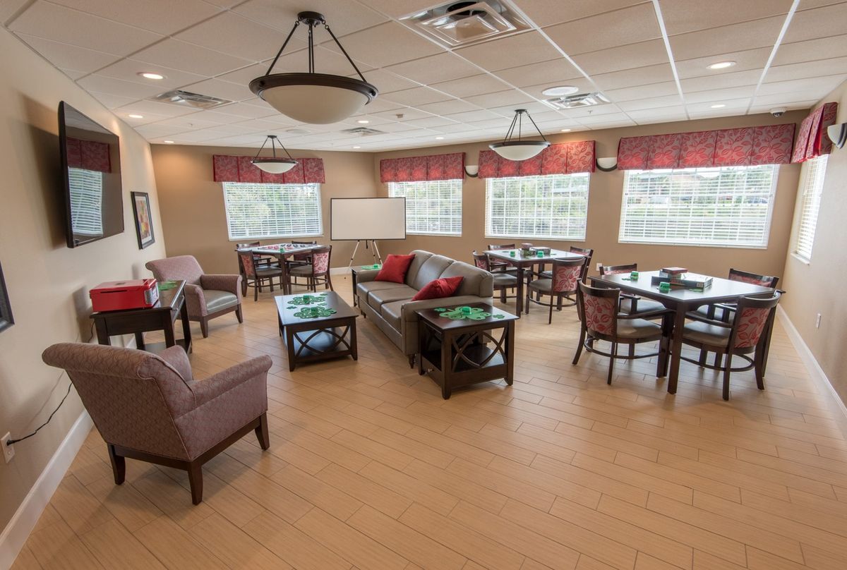 A comfortable lounge area with tables, chairs, sofas, and large windows.
