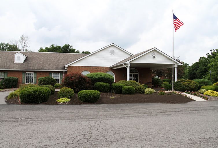 A one-story building with a landscaped front and an American flag next to the entrance.