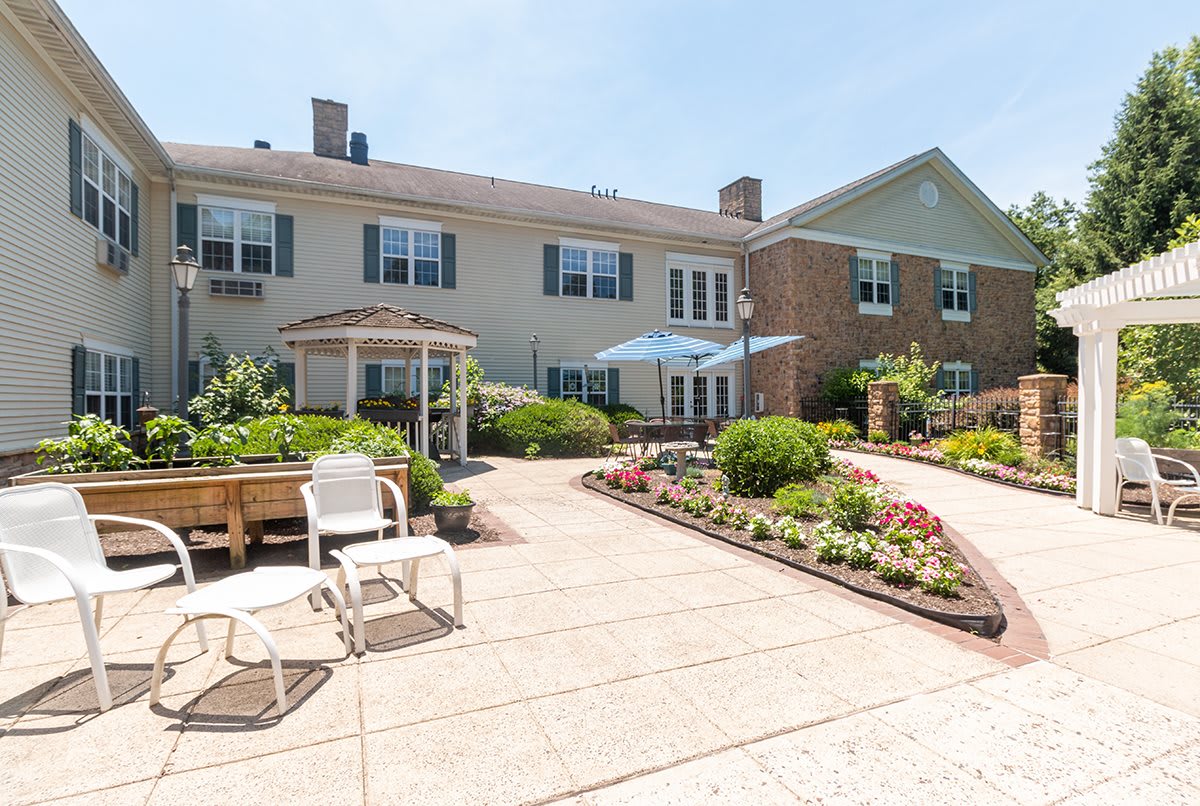 A charming building with a well-maintained garden and outdoor patio seating on a sunny day.