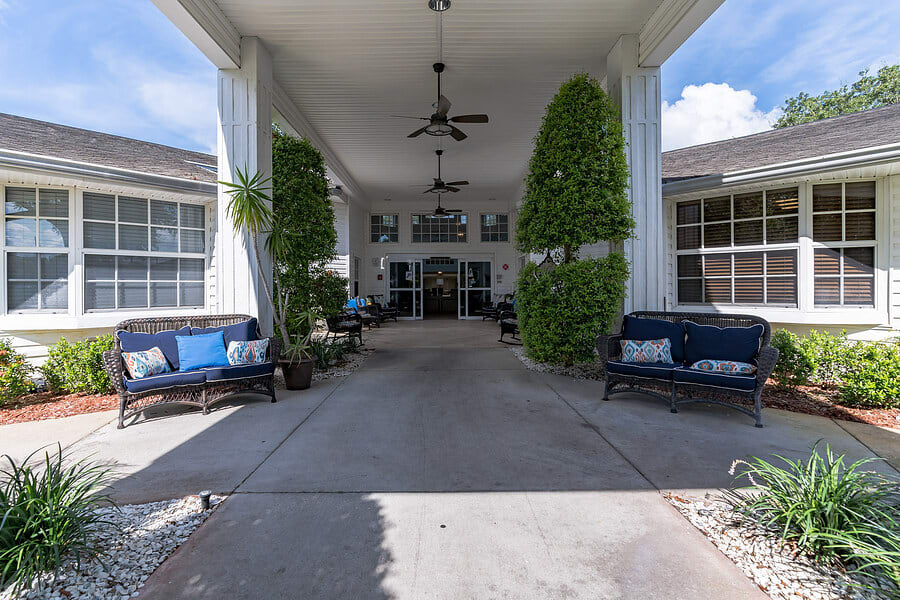 An inviting building entrance adorned with greenery and outdoor seating.