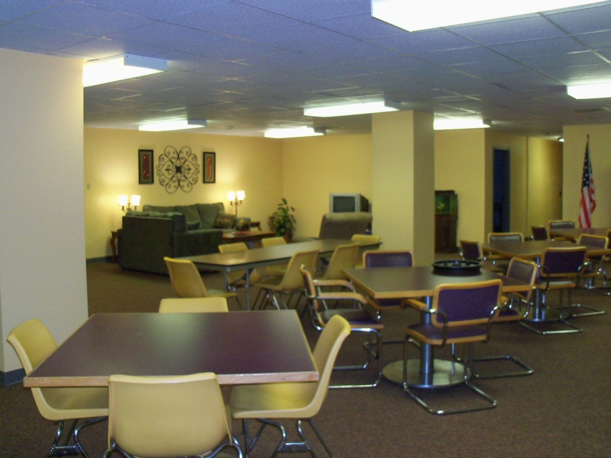 A spacious lounge area with tables, chairs, and sofas under bright lighting.