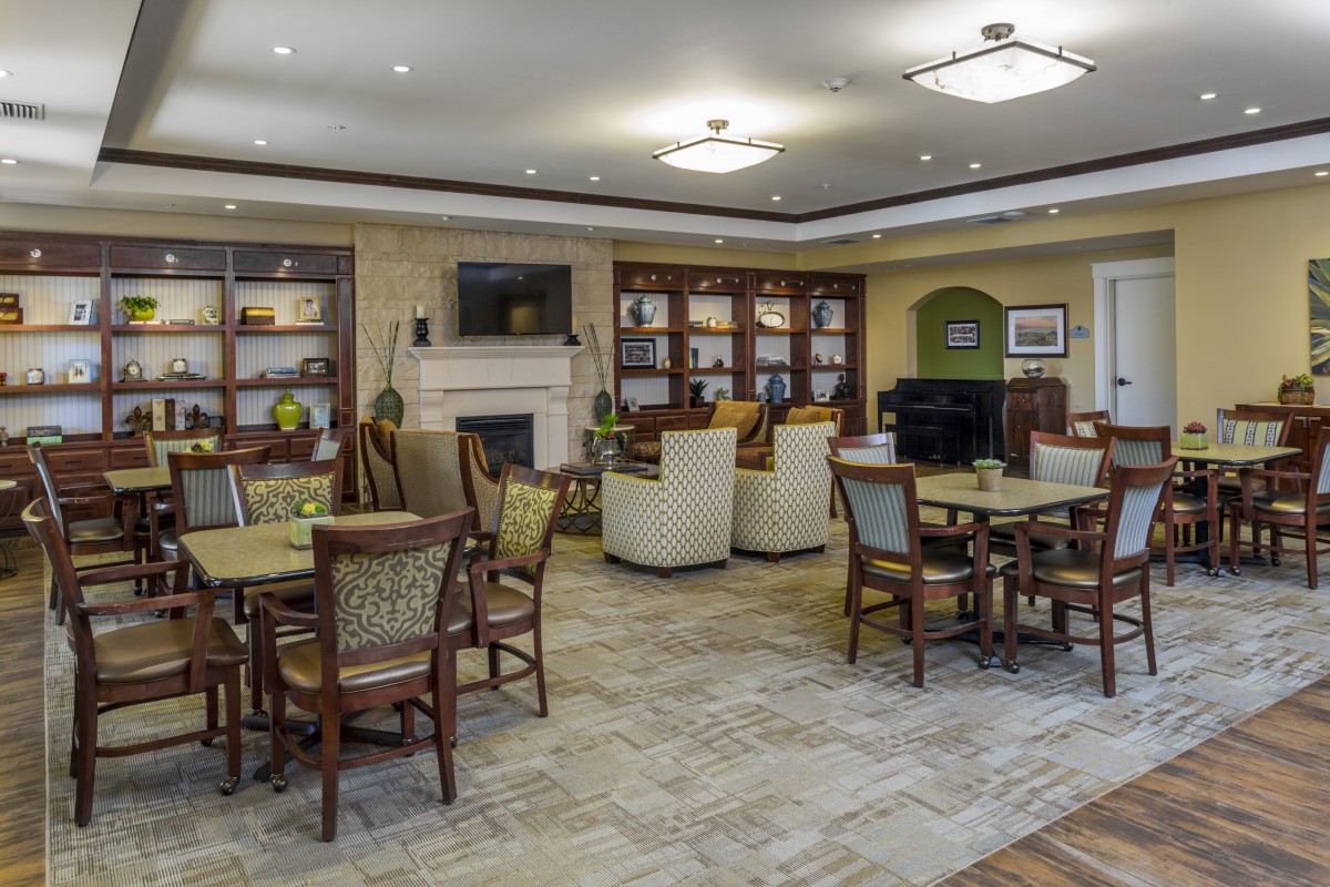 A cozy and well-furnished living area with multiple seating arrangements, bookshelves, a fireplace, and a television.