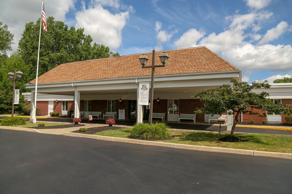 A brick funeral home with an awning and a cloudy blue sky in the background.