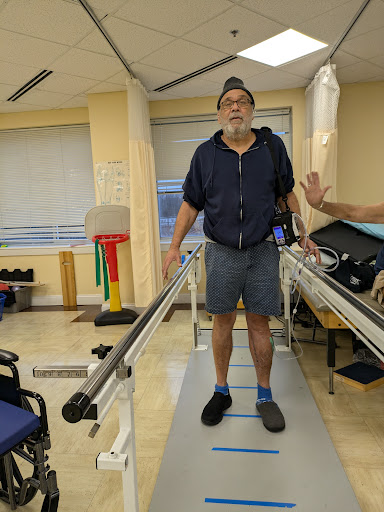 A patient undergoing physical therapy while standing on a walking assistive device.