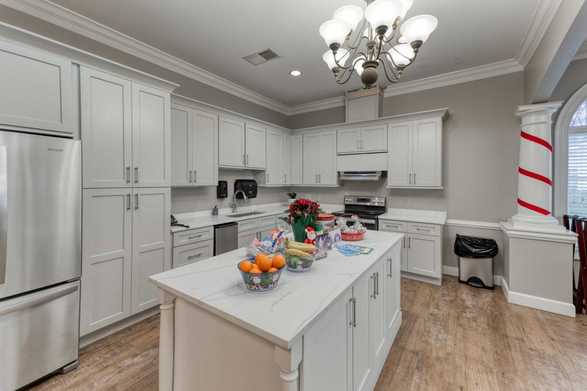 A modern kitchen with white cabinets, a central island, and a stylish chandelier.
