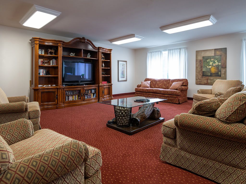 A cozy living room with a large TV, comfortable seating, and warm lighting.