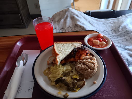A hospital meal featuring a variety of foods including a sandwich, mixed vegetables, fried chicken, and a colorful beverage.