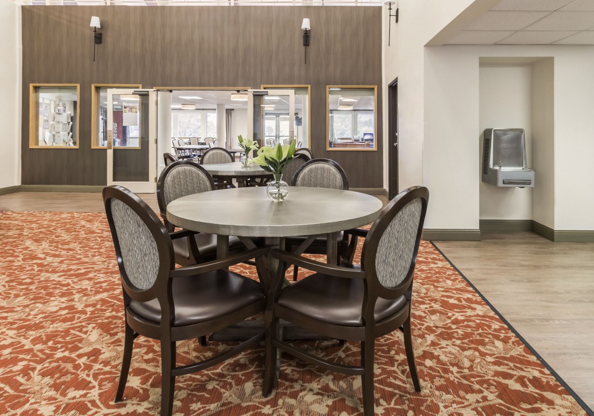 A cozy dining area with a round table and four chairs, set on a patterned carpet.