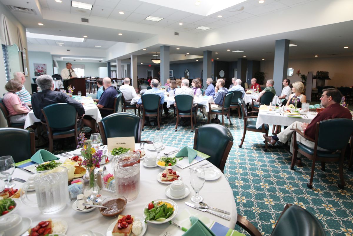 A formal gathering with people seated at tables, enjoying a meal in an indoor banquet setting.