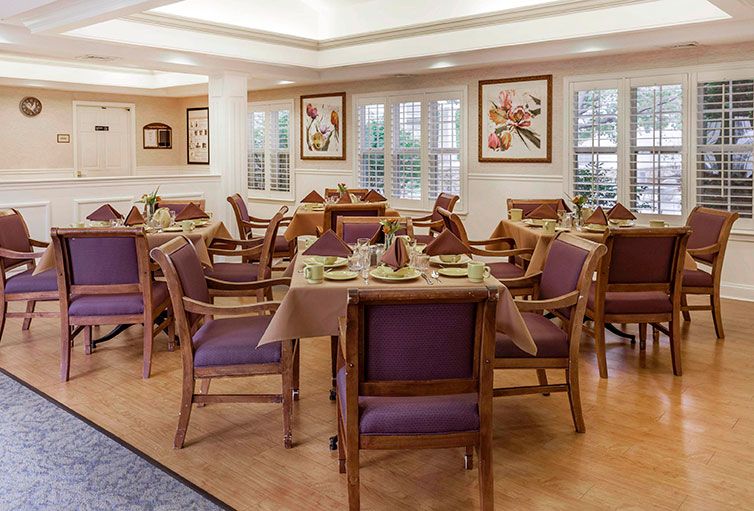 A well-lit dining room with neatly arranged tables and chairs, featuring tasteful wall decorations.
