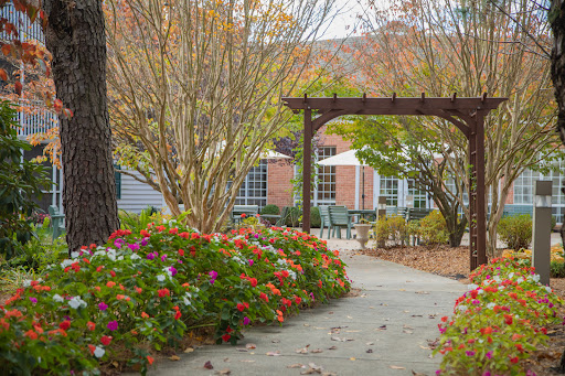 A tranquil garden pathway adorned with vibrant autumn flowers under an inviting archway.