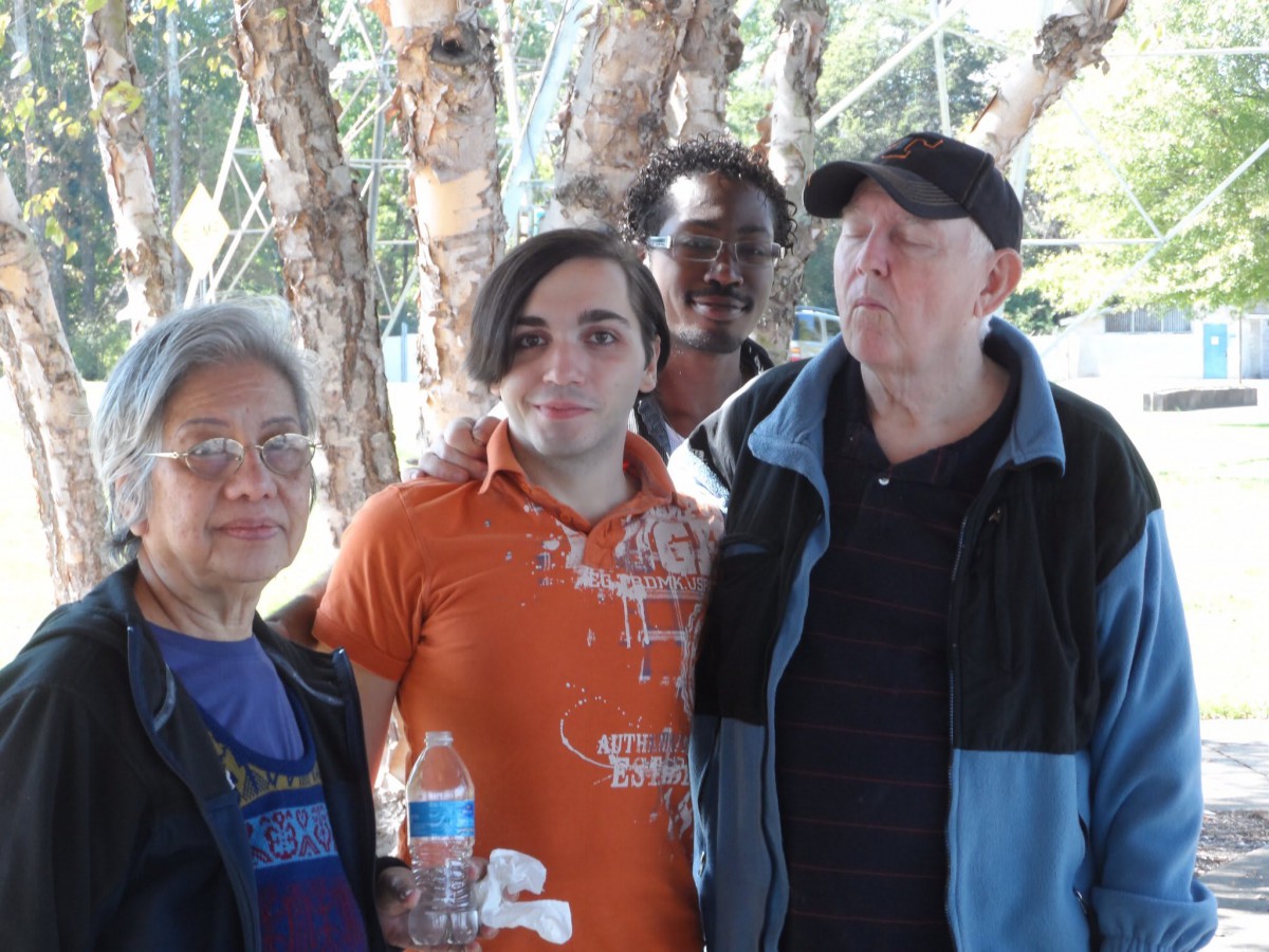A group of people posing together outdoors in front of trees.