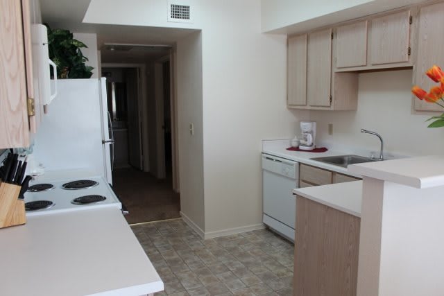 A modern apartment kitchen with appliances and light wood cabinets.