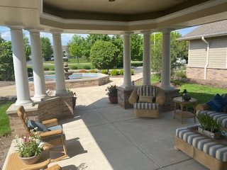 A serene patio with comfortable seating and a view of a lush garden.