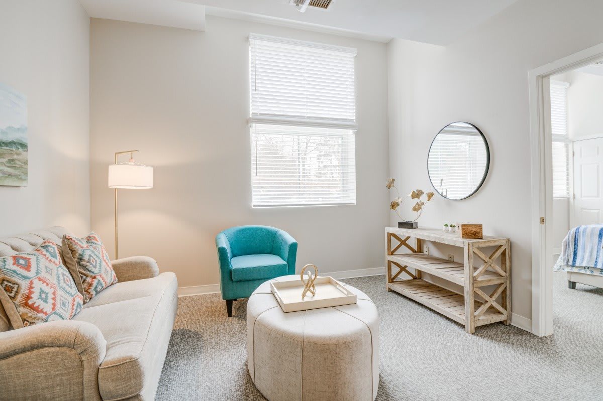 A modern living room with neutral tones, featuring a turquoise chair and stylish decor.