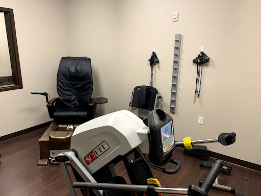 An exercise room equipped with various fitness machines and a comfortable chair for rehabilitation.