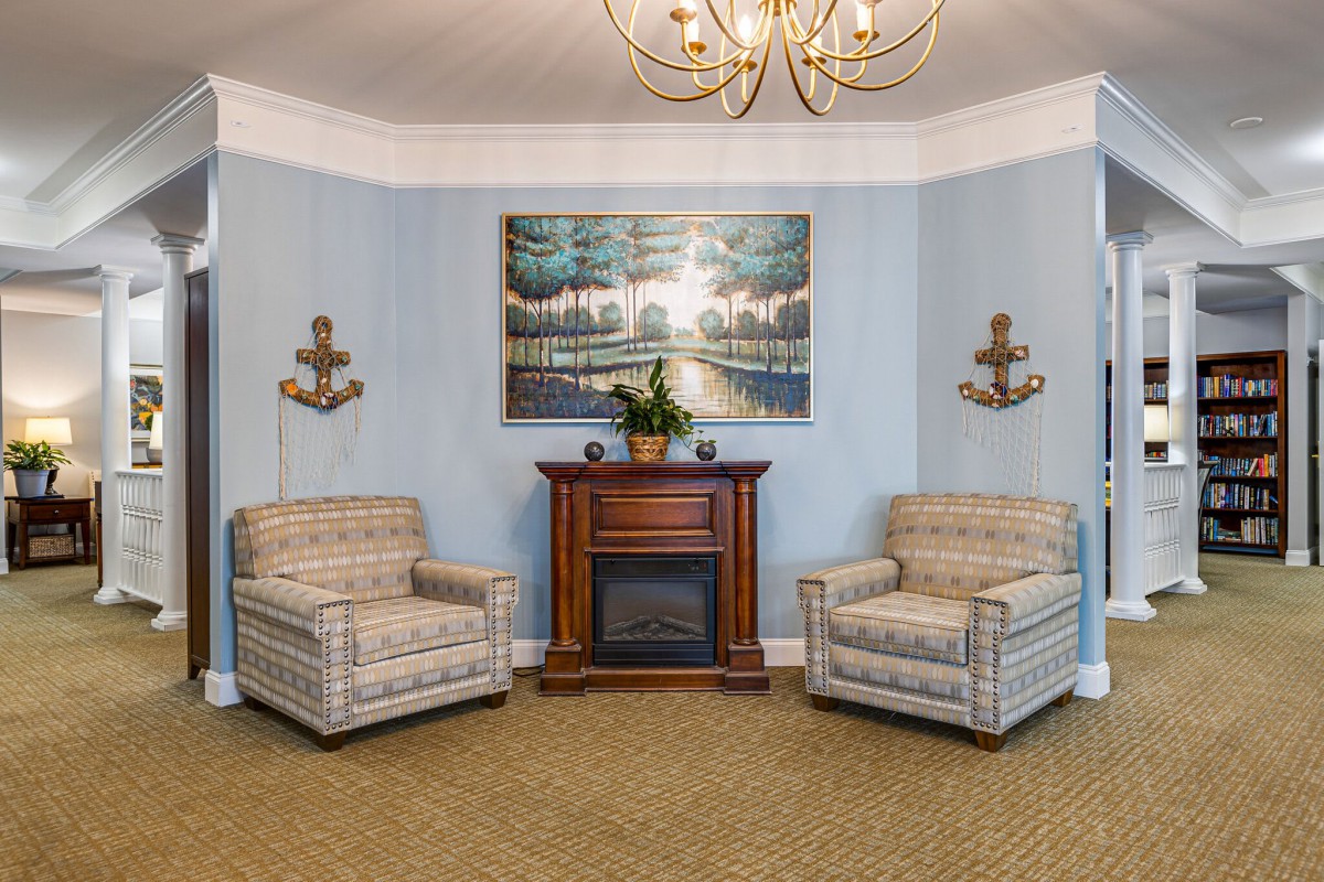 A cozy living room with two plaid armchairs, a central fireplace, and elegant wall decor.