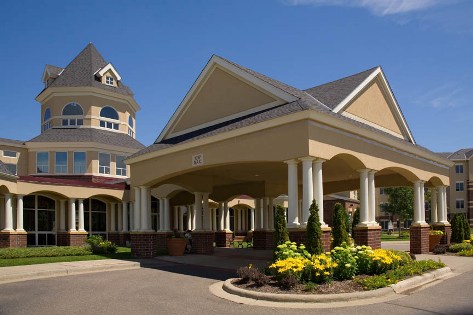 The elegant entrance of a hotel, featuring beautiful architecture and vibrant landscaping against a clear blue sky.