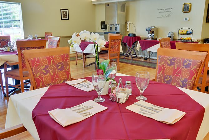 A cozy restaurant interior with neatly set tables and vibrant red tablecloths.