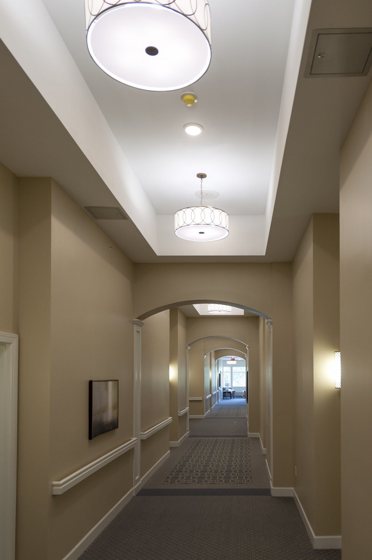 A well-lit hallway with beige walls and an elegant ceiling light fixture.