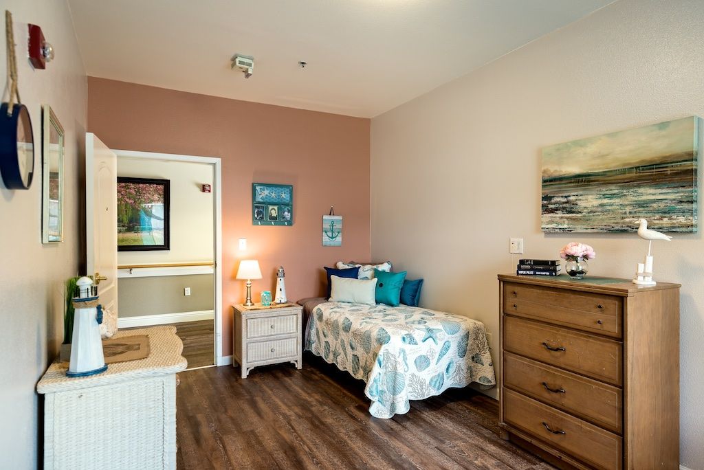 A cozy bedroom with a single bed, wooden flooring, and bright decorations.