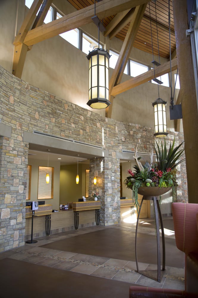 A modern lobby featuring stone walls, elegant lighting, and a decorative floral arrangement.