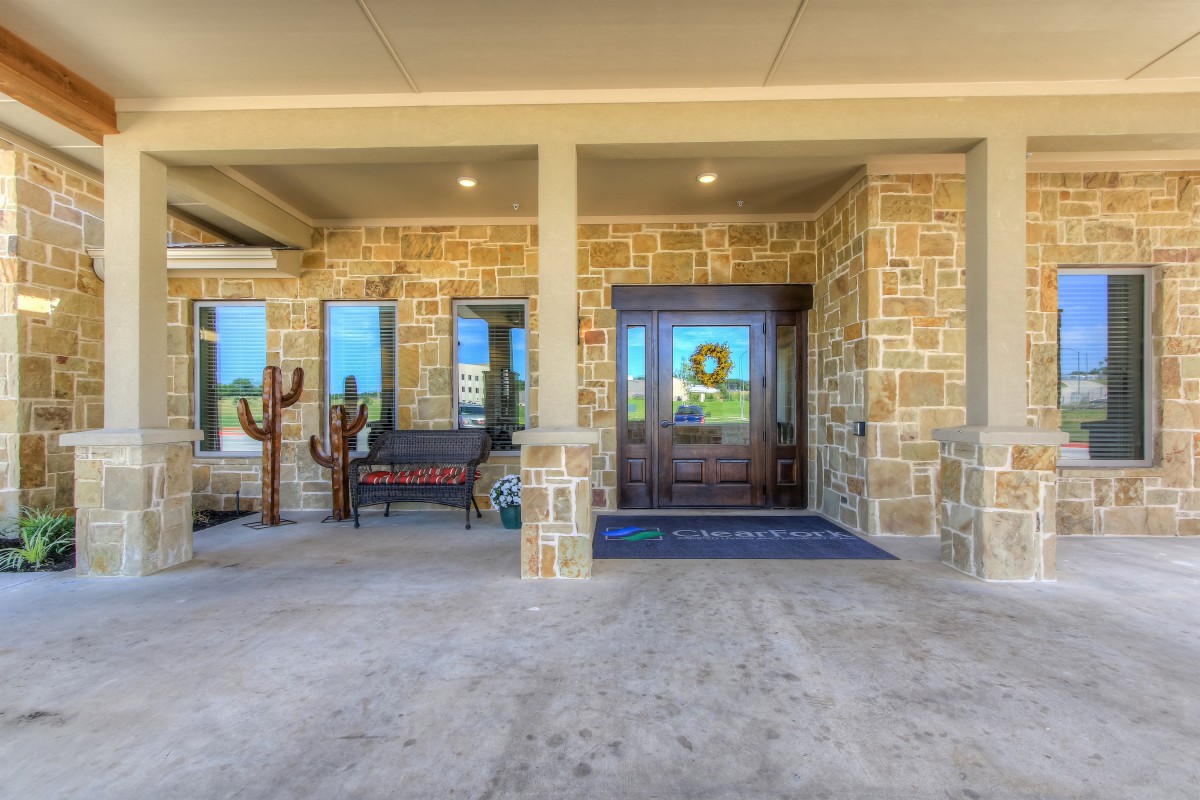 A welcoming stone exterior entrance with a bench and decorative cactus.