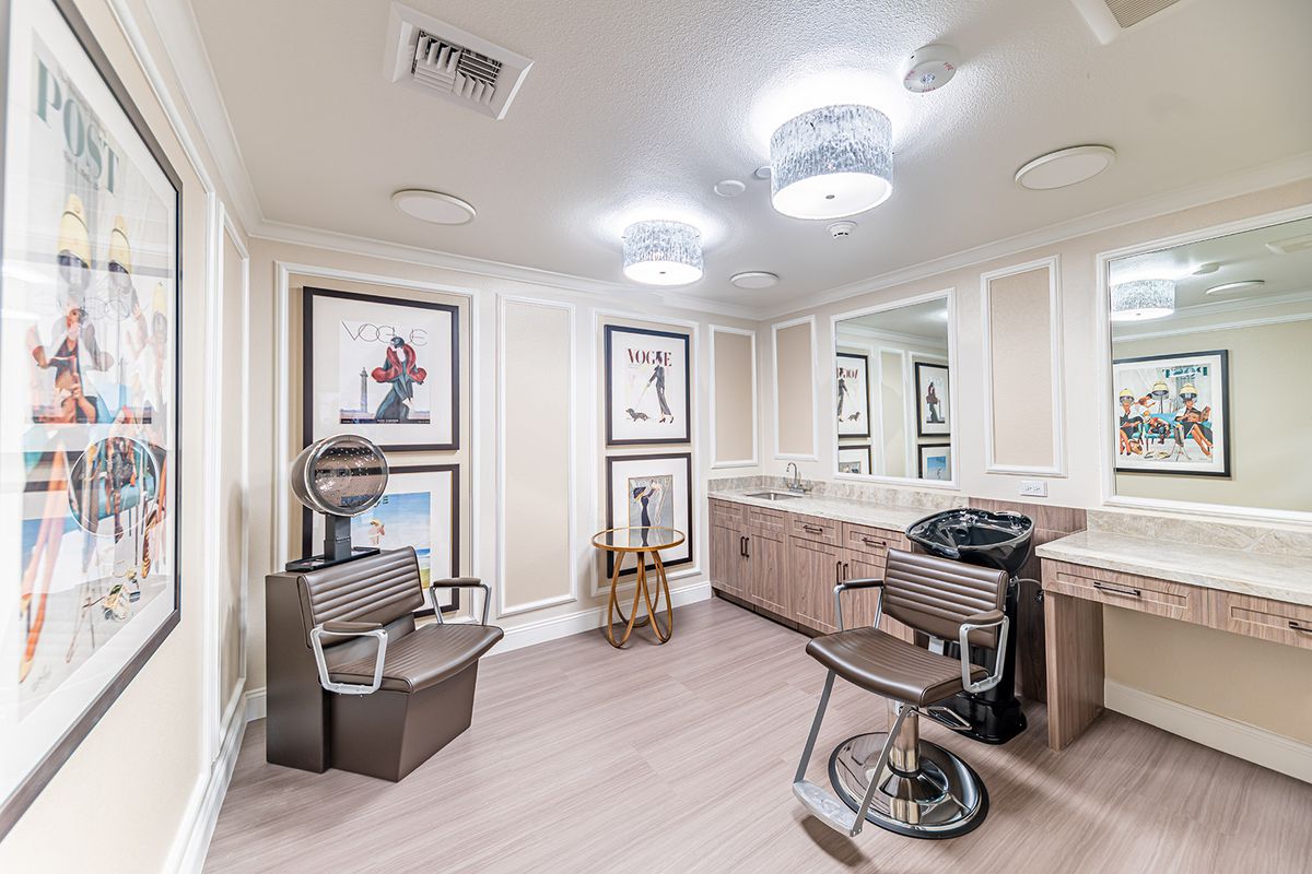 A modern hair salon interior featuring stylish barber chairs, large mirrors, and contemporary wall art.