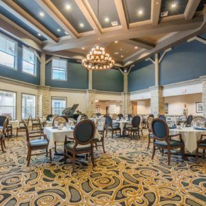 A spacious and elegantly decorated dining room featuring chandeliers and large windows.
