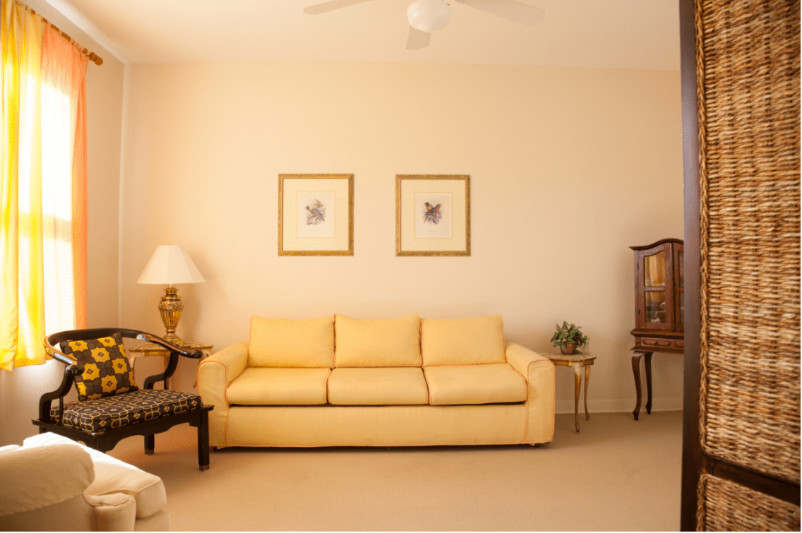 A cozy living room with a yellow sofa, elegant lamp, and framed artwork.