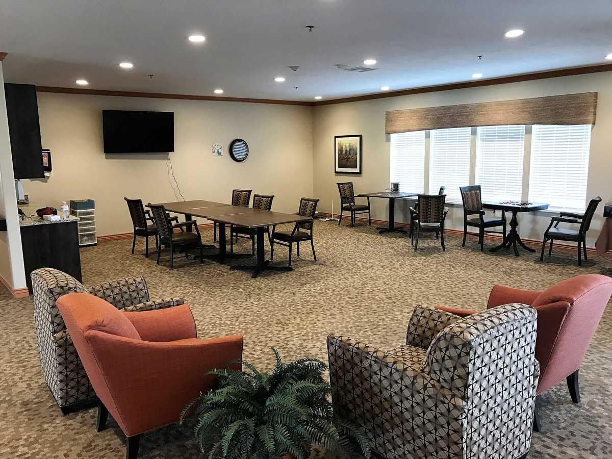 A well-lit conference room with a large table, chairs, and a television.