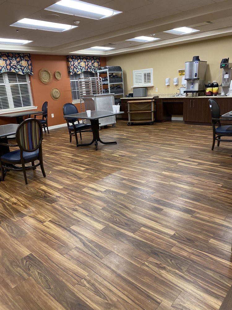 An empty dining area with wooden floors, tables, and chairs.