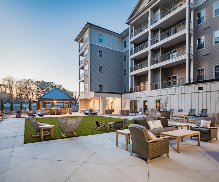 A modern apartment building features a spacious outdoor courtyard with comfortable seating.