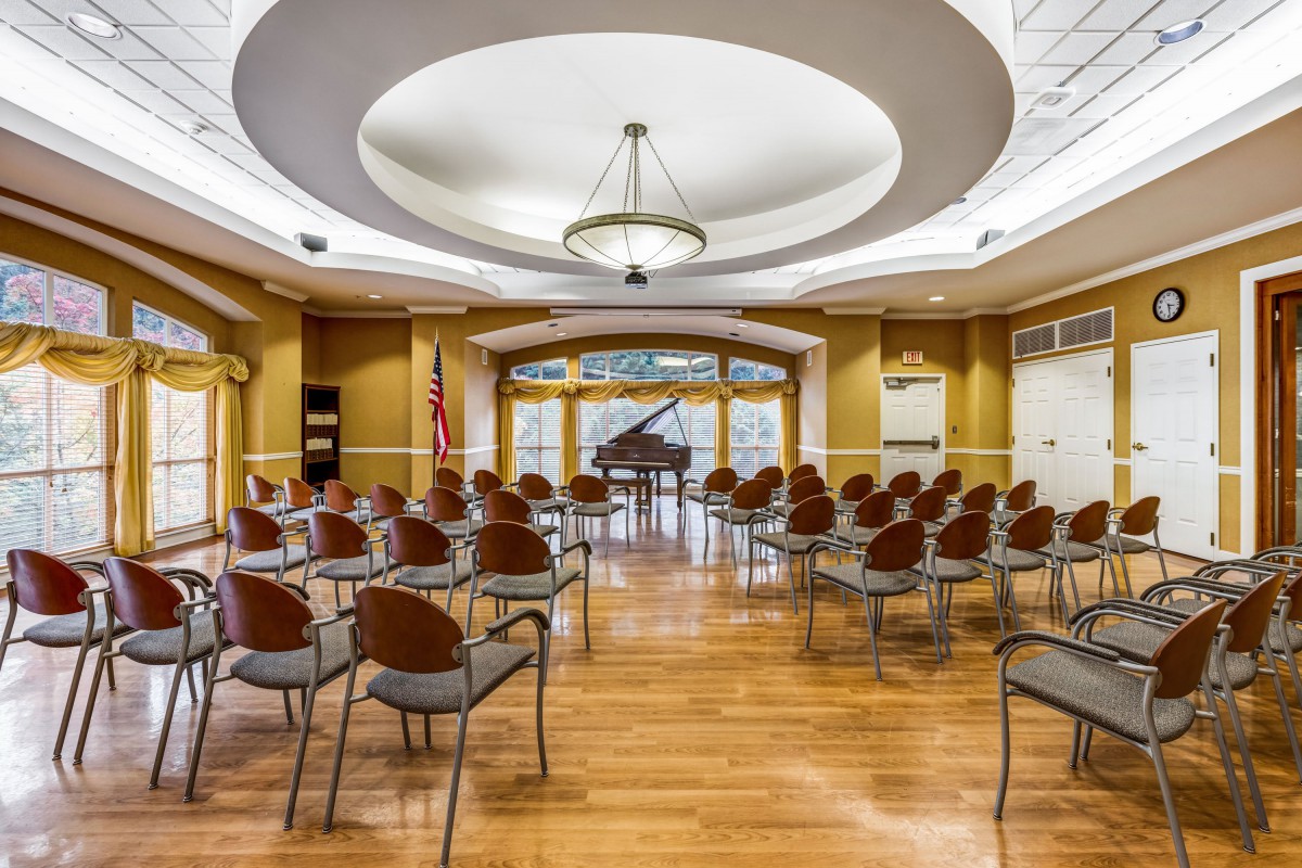 A well-lit meeting room set up with chairs facing a piano.