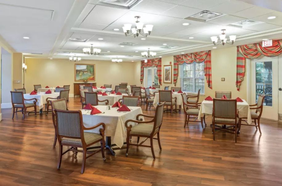 An elegant dining room with neatly arranged tables and chairs, accentuated by warm lighting and wooden floors.