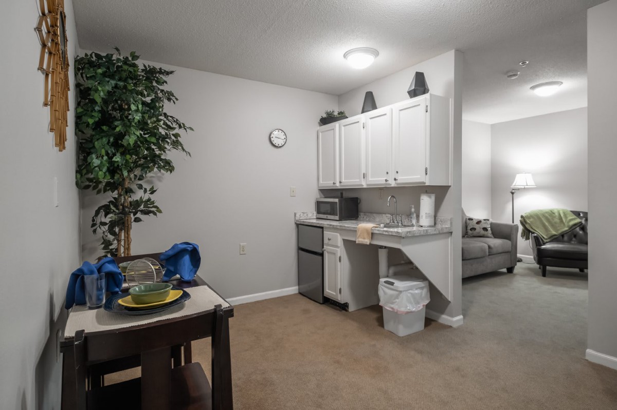 A cozy kitchen with a small dining area, featuring white cabinets and a table set for two.