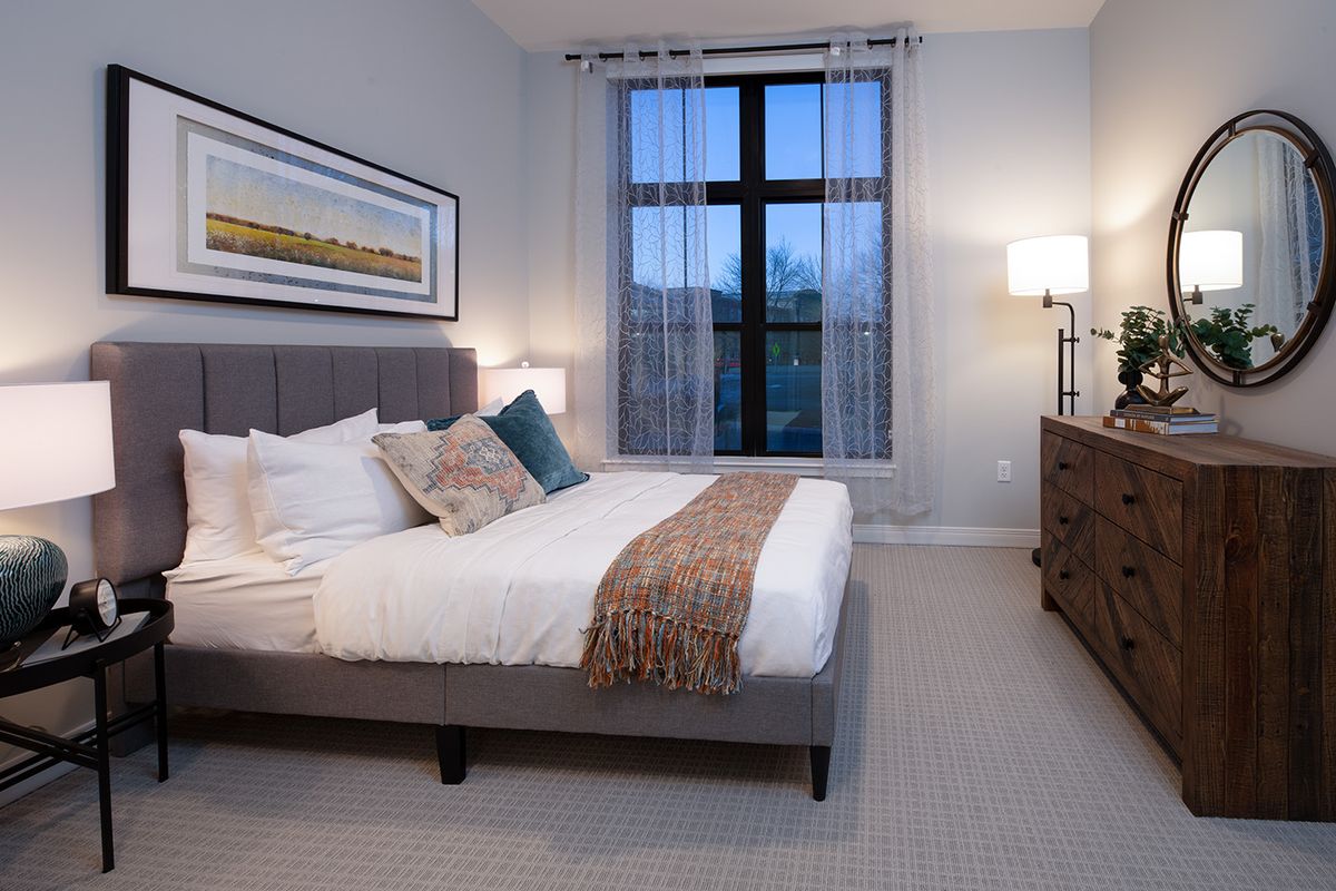 A modern bedroom with a cozy bed, decorative pillows, and a large window providing natural light.