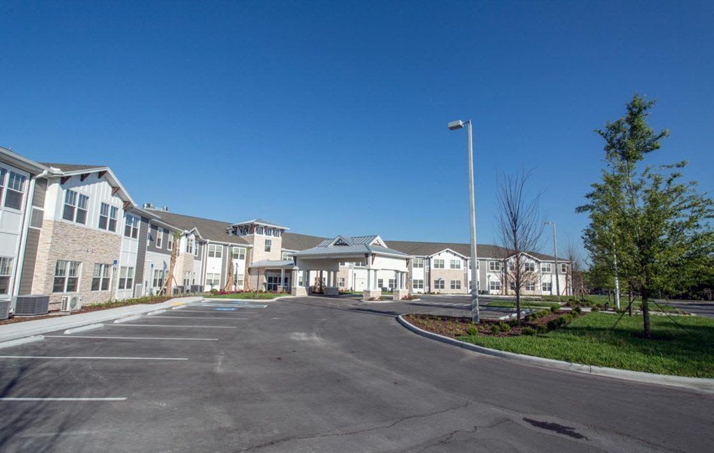 A wide-angle view of a large building with an empty driveway and clear blue sky.