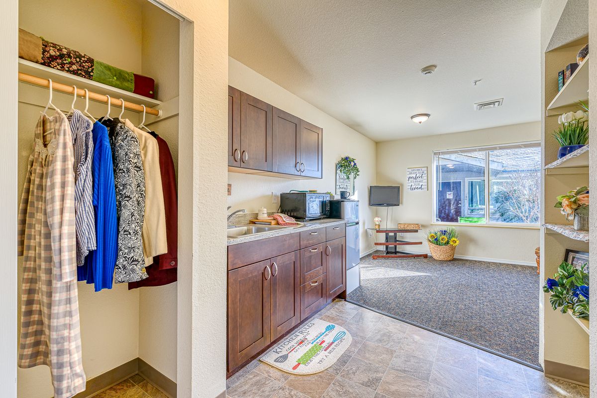 A cozy open-plan kitchen and living space with cabinetry, appliances, and a closet, bathed in natural light from a large window.