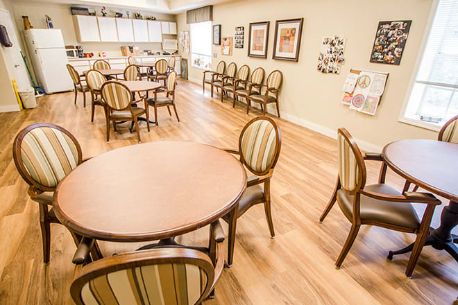 A well-lit dining area with neatly arranged tables and chairs on a wooden floor.