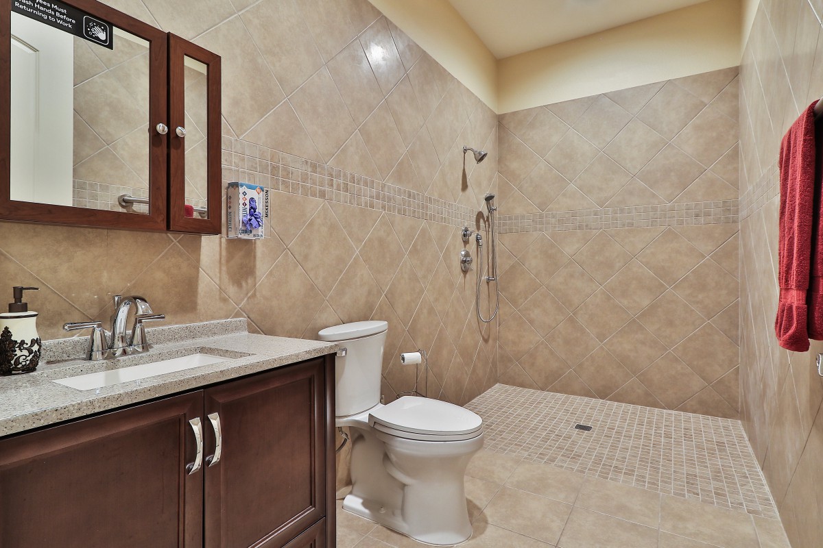 Spacious bathroom with a modern design featuring a walk-in shower and wooden vanity.