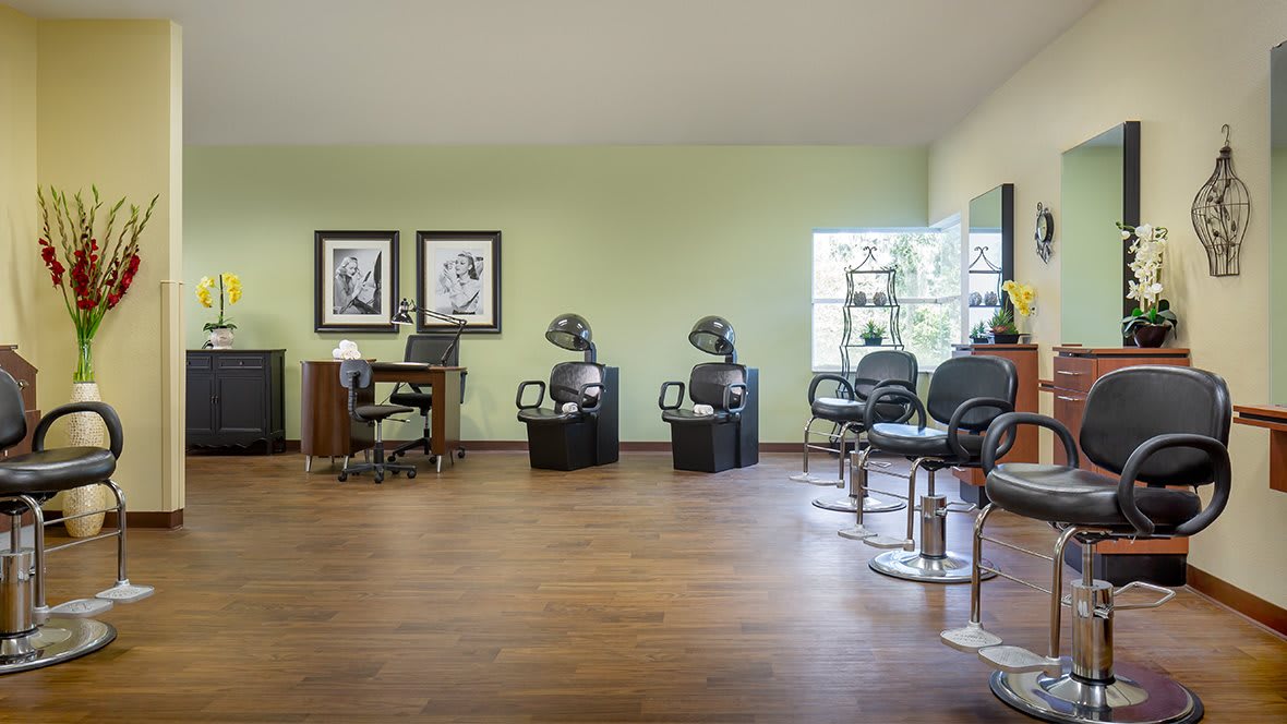 A modern hair salon interior with styling chairs and dryers.