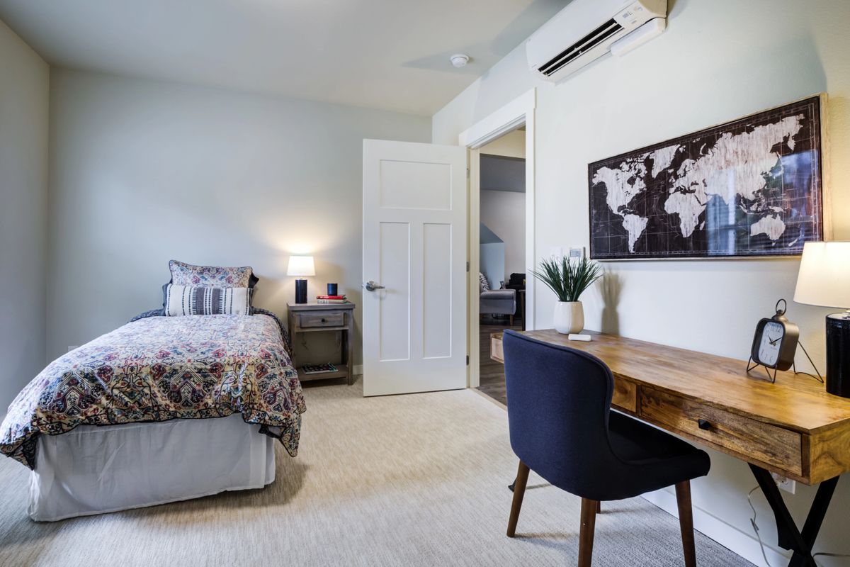 A modern minimalist bedroom with a neatly arranged desk and map artwork on the wall.