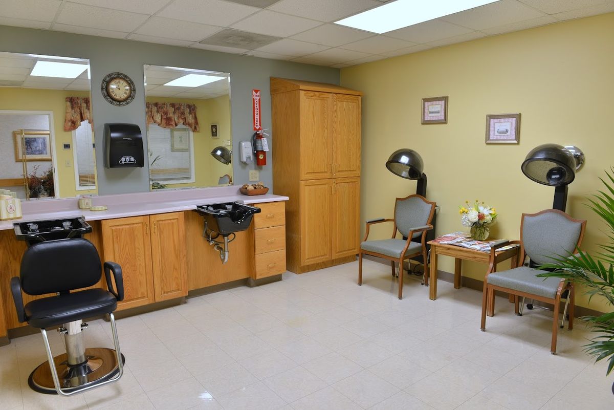 A hair salon with a waiting area featuring chairs and a hair dryer next to a counter with a mirror.