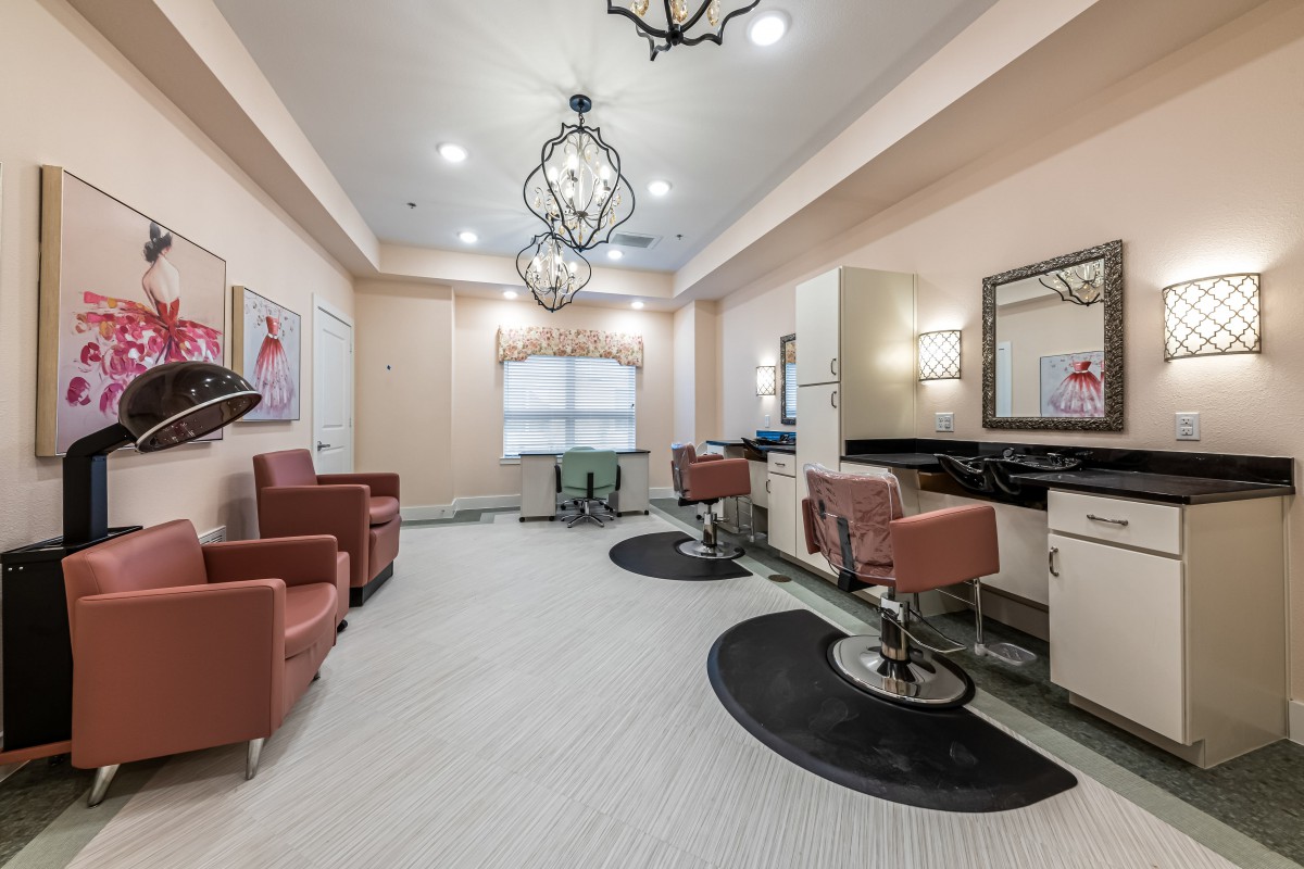 A modern hair salon interior featuring stylish chairs, mirrors, and elegant chandeliers.