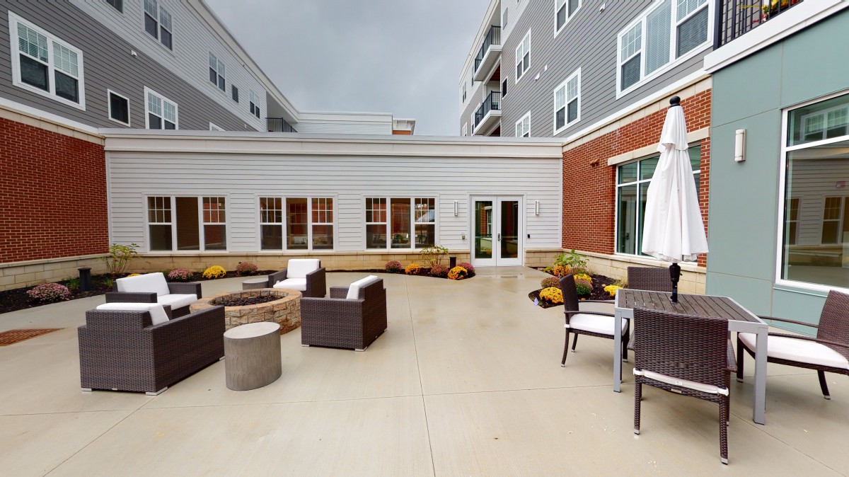 A modern outdoor patio with comfortable seating, surrounded by an apartment building.