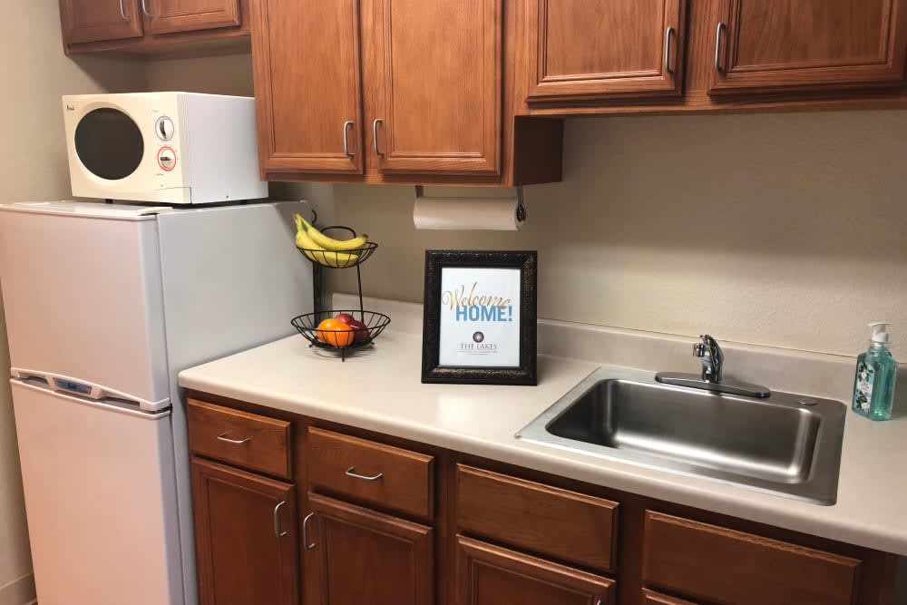 A cozy kitchen countertop with a fruit basket and framed artwork next to the sink.